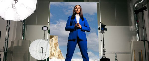 Poster image of Asiya Rao standing on a photoshoot set in a tory blue suit.