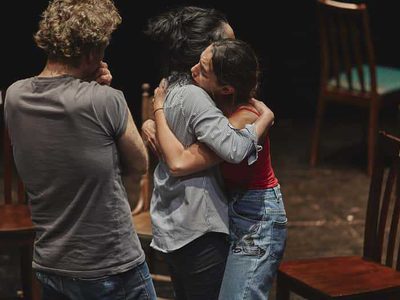 Two of the actors emotionally embrace. The director Patrice looks on.