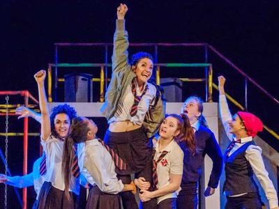 Young women celebrate with their hands in the air - one is held aloft