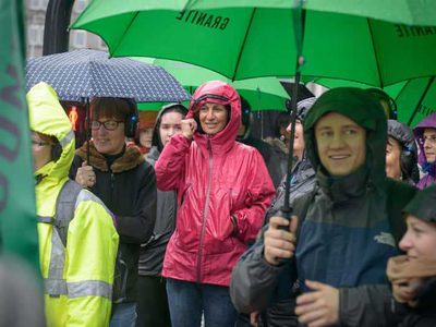 A group of smiling people with green umbrellas