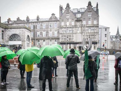 A group of people stand in front of a large granite building