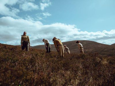 Five people leaning back with hills behind them
