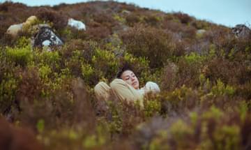 Person in beige outfit lying in wild plants