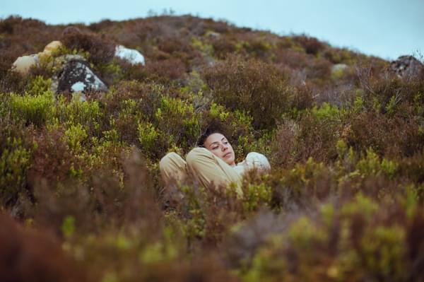 Person in beige outfit lying in wild plants
