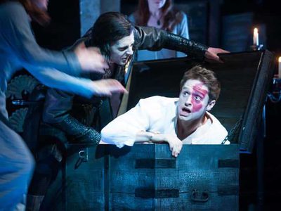 A young man with a red birth mark on his face is in a wooden box looking frightened.