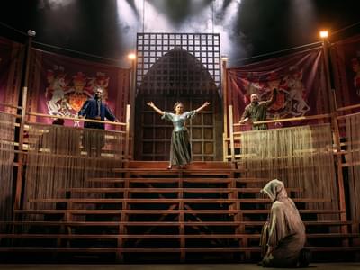 The actors stand triumphantly atop an ornate set, dressed in period clothing