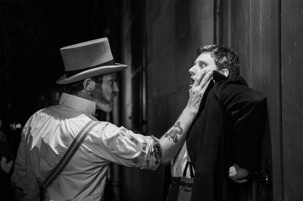 An actor with mutton chops and a top hat threatens another