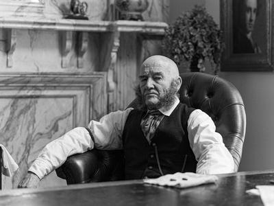 Tam Dean Burn sits scowling in a large leather chair
