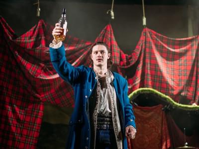 An actor in pirate attire raises a bottle of alcohol