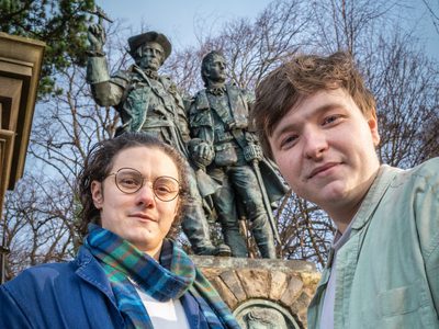 Selfie of two lead actors in front of a statue
