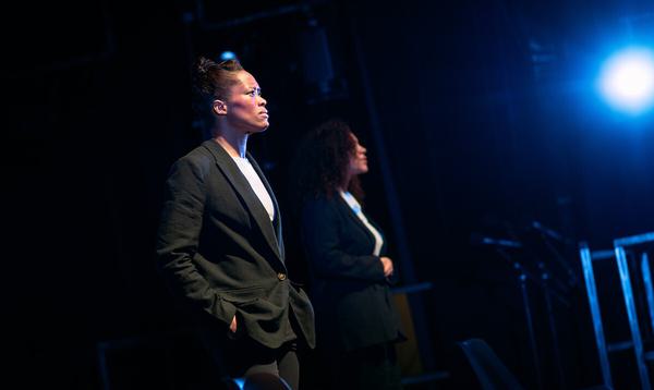 Two women in suit jackets stand side by side