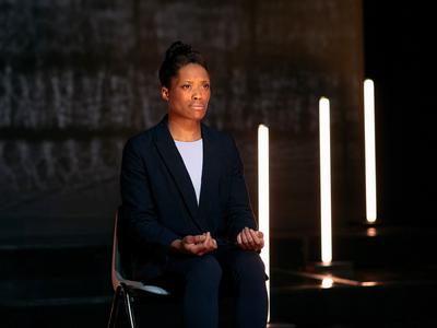 A woman sits with her hands upturned in her lap