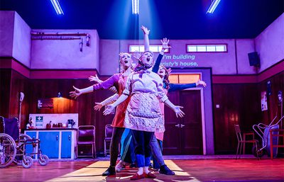 The cast sing, standing in a line and making jazz hands