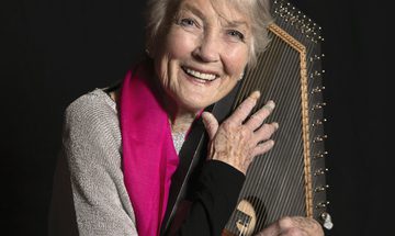 A woman holding a small harp-like instrument