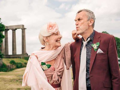 A grey-haired couple wearing formal clothes, teasing one another