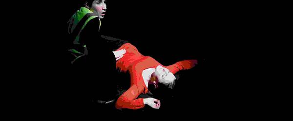 A person in red sprawled on the ground, a person in high visibility clothing crouched beside them