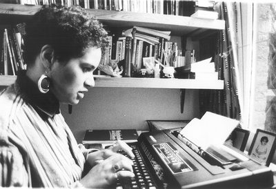 A black and white photo of the author Jackie Kay as a young woman sitting at a typewriter.