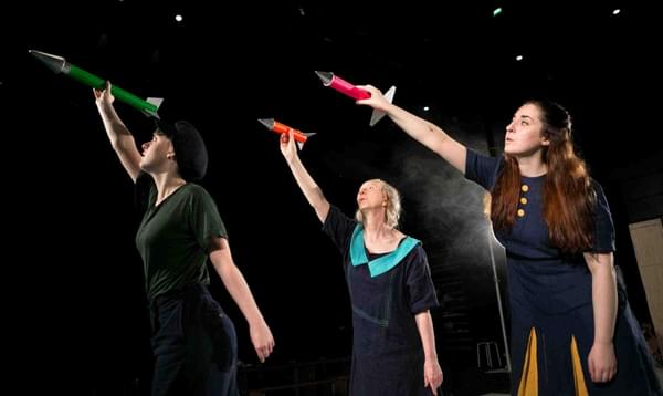 Three women hold rockets above their heads to make them fly.