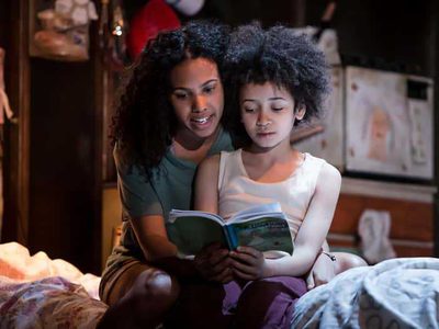 A little boy cuddles next to his mum and they read a book together