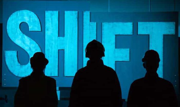Three silhouetted figures stand in front of a sign that says shift