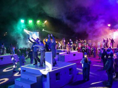 People in overalls and head torches stand in front of an epic crane