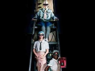The three slumber sisters sitting on a lookout ladder wearing goggles