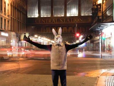 A human size bunny stands in front of Glasgow Central Station at night time