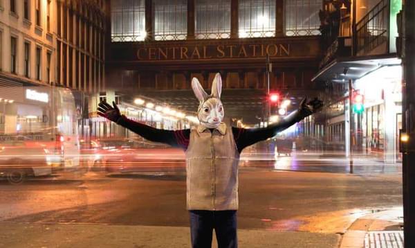 A human size bunny stands in front of Glasgow Central Station at night time
