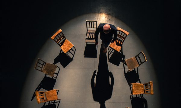 A hand opens a large hardback book. The cover is white with bold black text reading 'Total Immediate Collective Imminent Terrestrial Salvation;