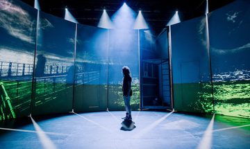 Actor standing in the middle of the stage with a light from the top illuminating them creating contre-jour lighting