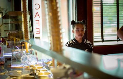 A young girl in a black tracksuit in an ice-cream cafe