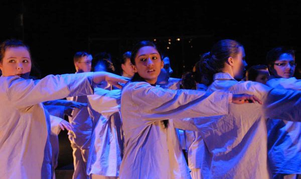 Group of performers wearing grey and holding arms out