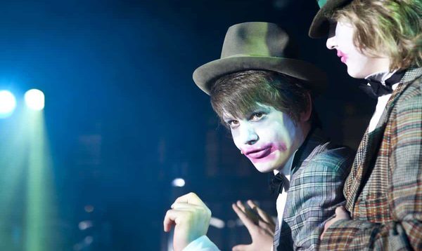 Two performers in hats with pink make up over their mouths