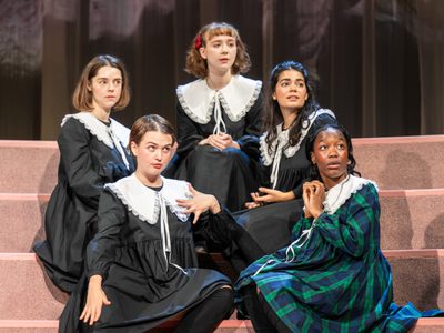 Five girls sit on the steps, they watch something off-camera curiously