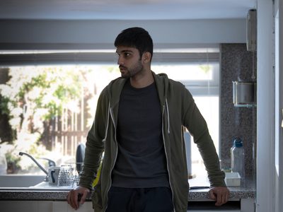 Sani Mamood leans against a kitchen counter in front of a window looking worriedly to his right.