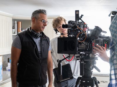 Kal Sabir and crew members stand in a kitchen around a film camera setting up a shot