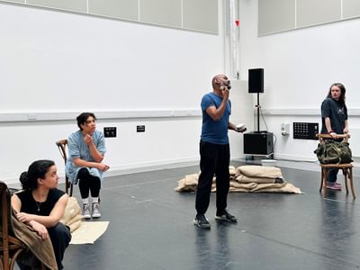 Ramesh stands in the rehearsal room, he is shaving. The three actresses watch not knowing what to make of the situation.