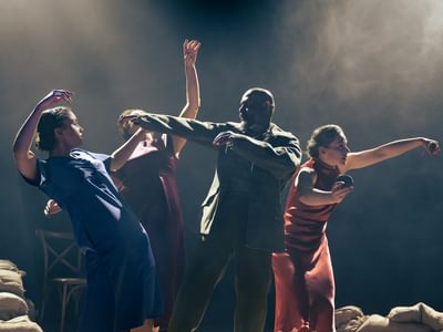 Four performers are on-stage. Each one has contorted their bodies by bending and holding their arms out. The light has cast a shadow on everyone's face making the scene strange and unsettling.