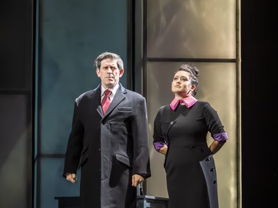 Andy Clark and Charlotte Delima stand on stage. They both wear smart clothing which is mostly black with pink accents. Maya has her arms behind her back, she seems confident and proud. Andy surveys his surroundings.