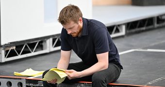 Actor Jack Lowden sits on the edge of the rehearsal stage reviewing his script.