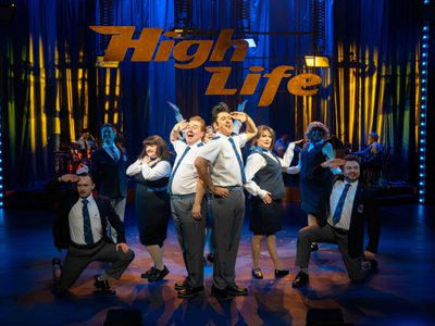 A group of people pose in front of a sign which reads 'High Life'