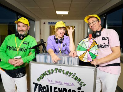The Trolleydarity team stand with their trolley. They smile and are very colourful.