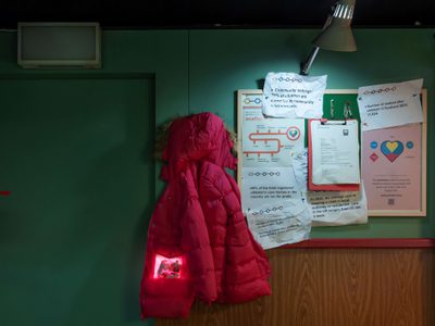 A pink jacket hangs on a wall next to information leaflets on the Care System